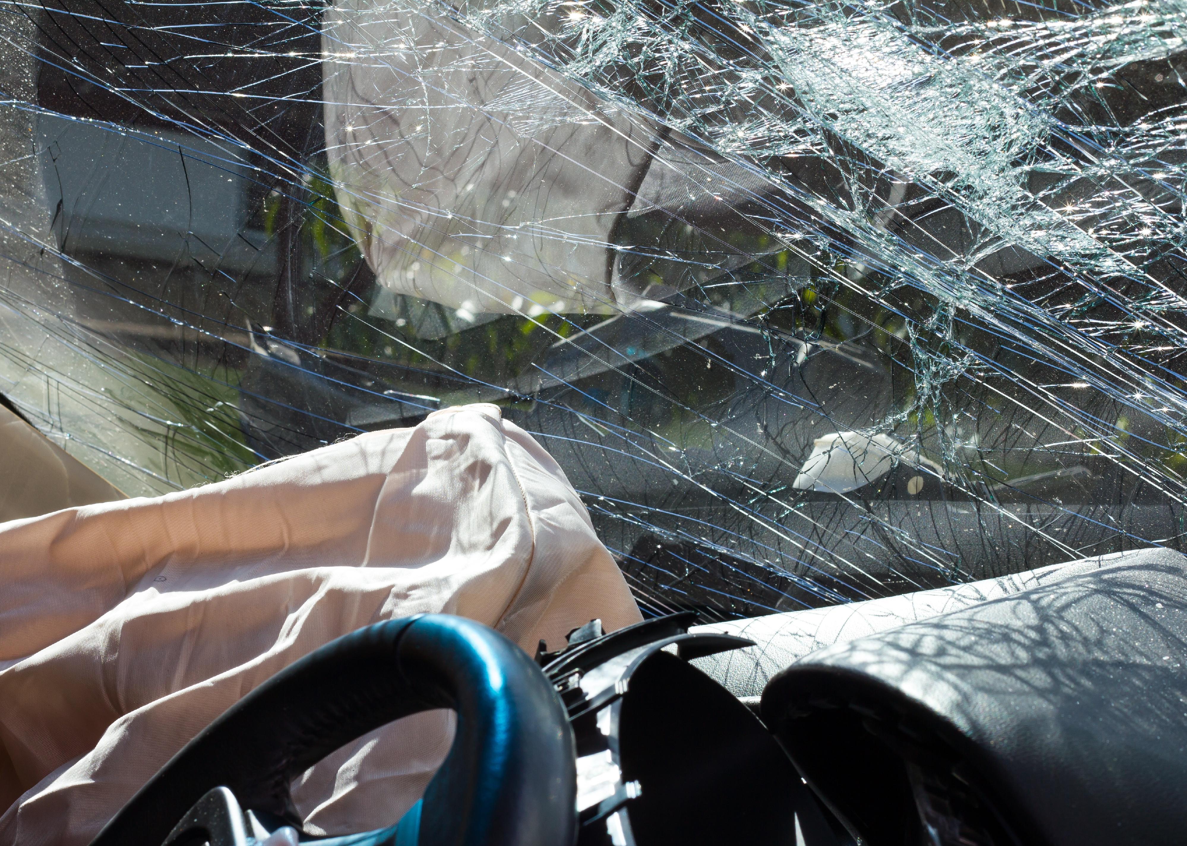 Inside a car with airbags and windshield cracks.