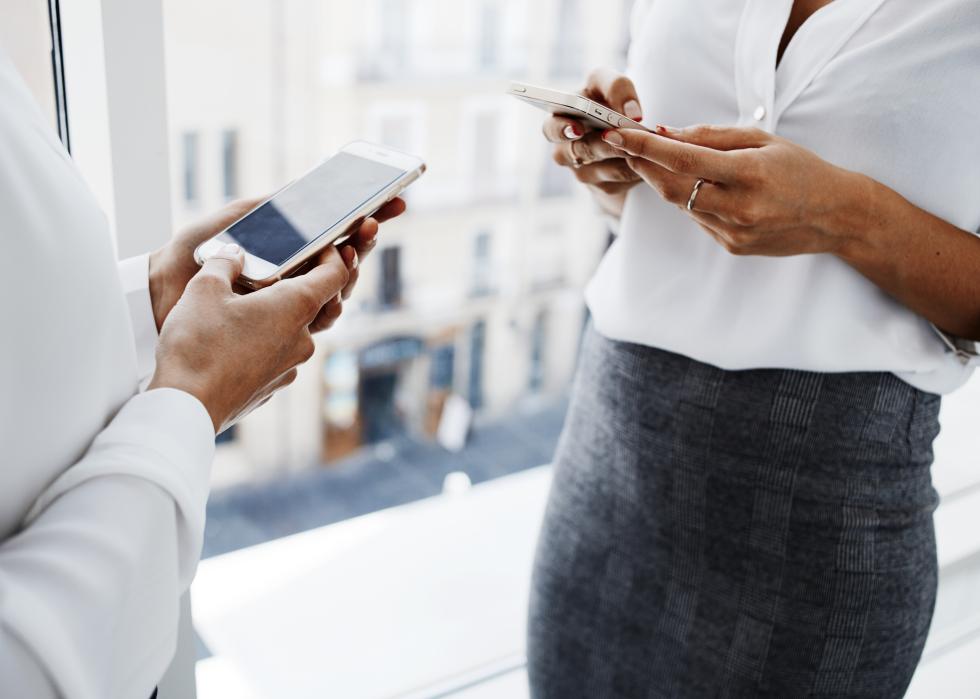 Two young female professionals using cell phones to send payment.