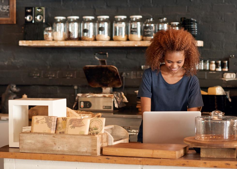 Woman behind a cafe counter on laptop