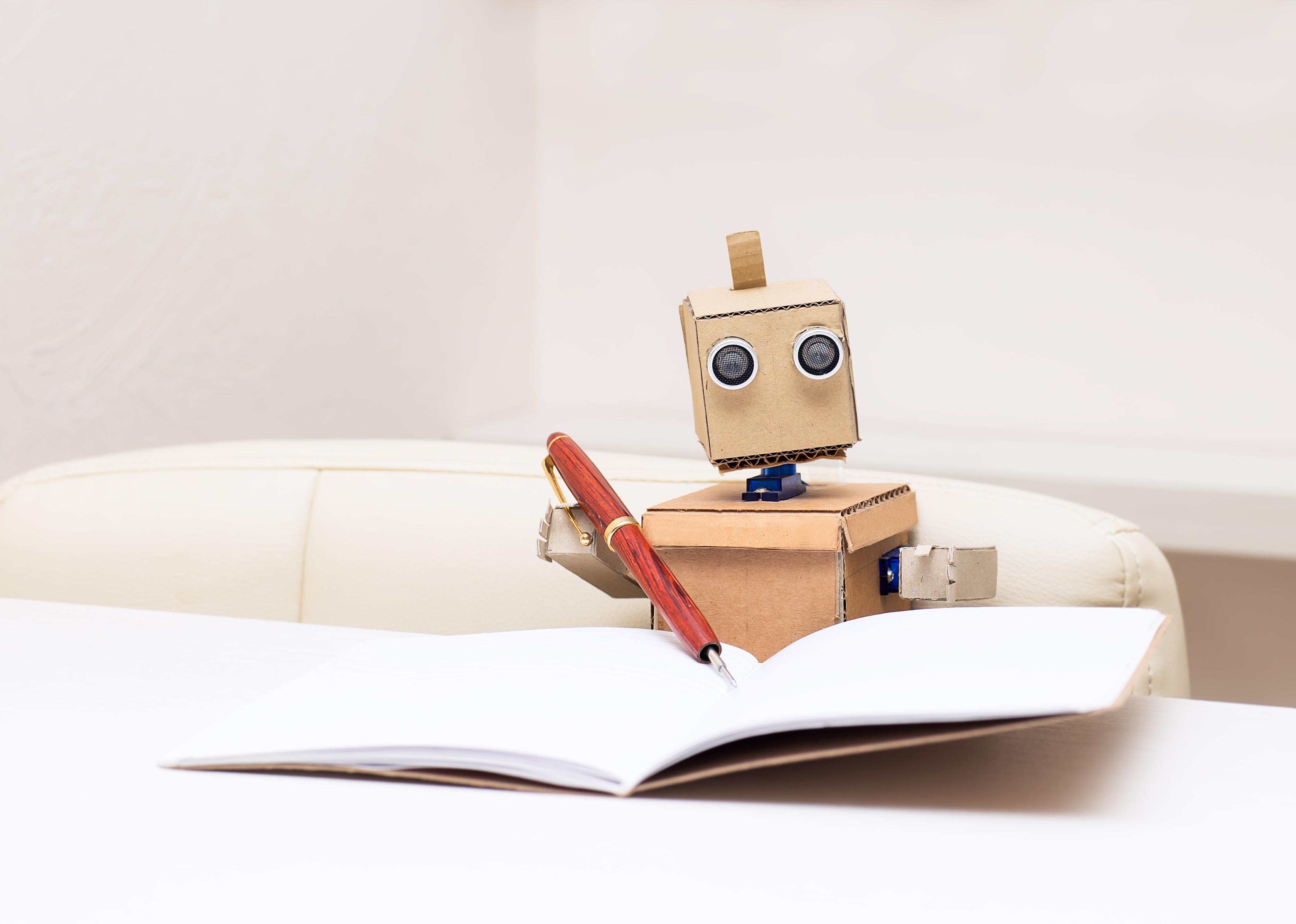 Robot writes with a ballpoint pen and sitting at the table.