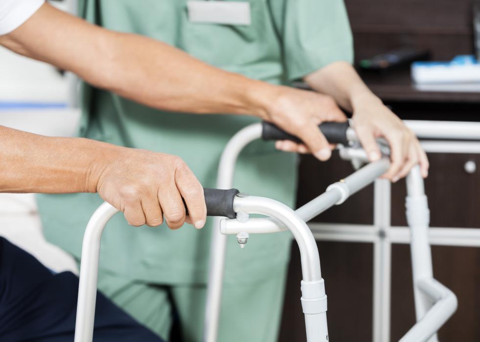 Patient's hands holding a walker next to a nurse.