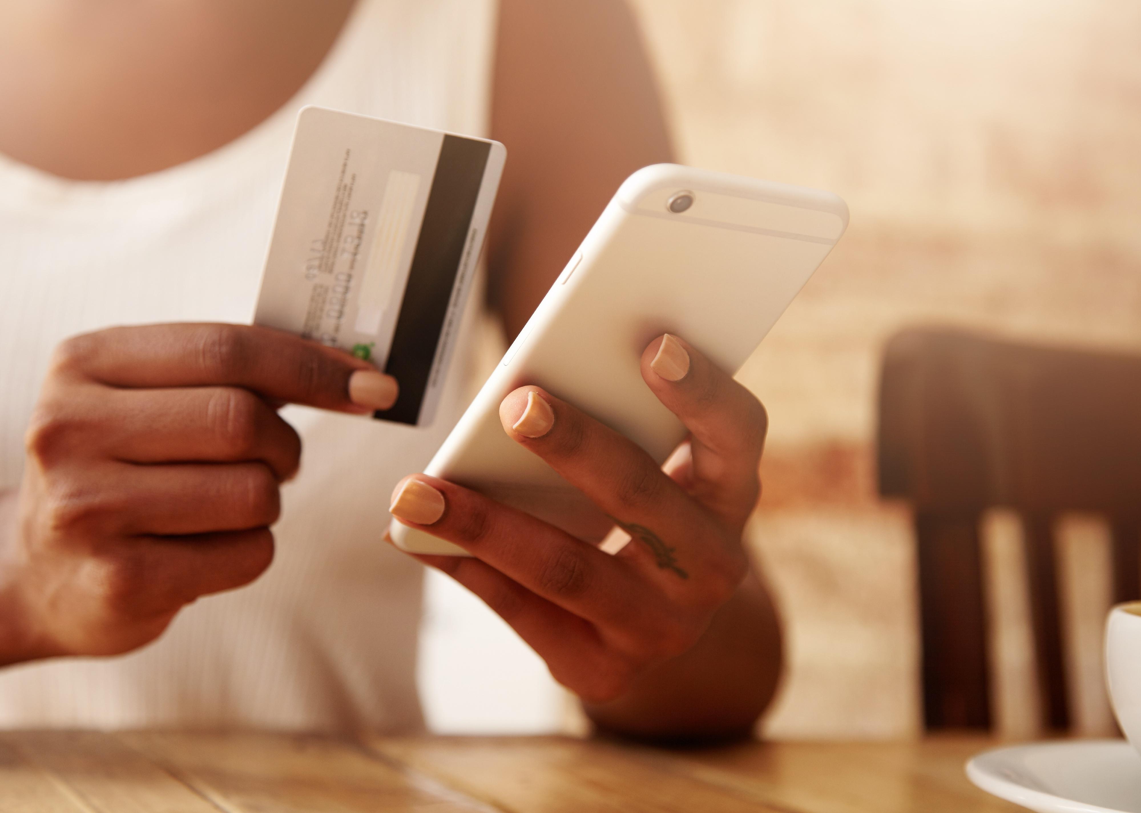 Close-up of hands holding credit card and mobile phone