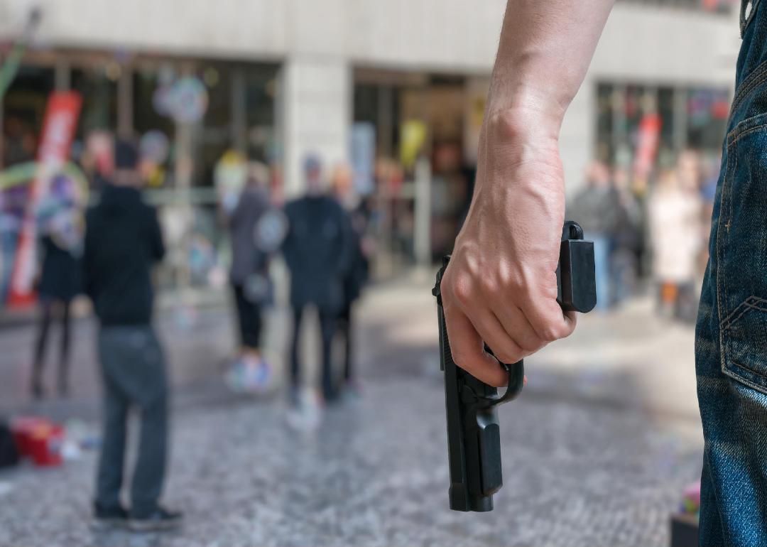 A person's hand holding a handgun in a crowded area. 