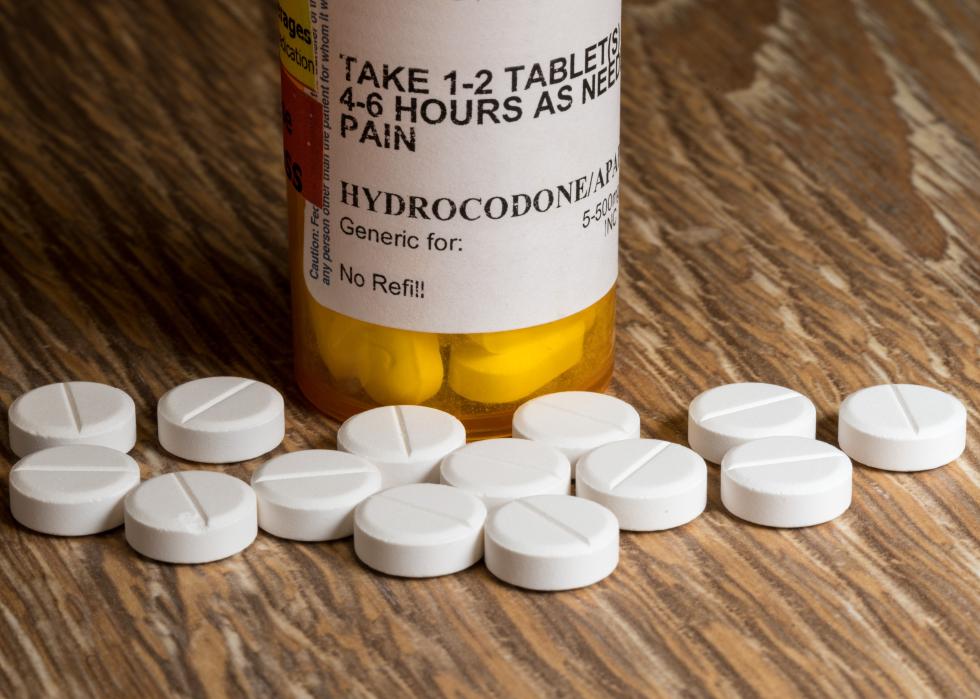 Prescription bottle for Oxycodone tablets and pills on wooden table.