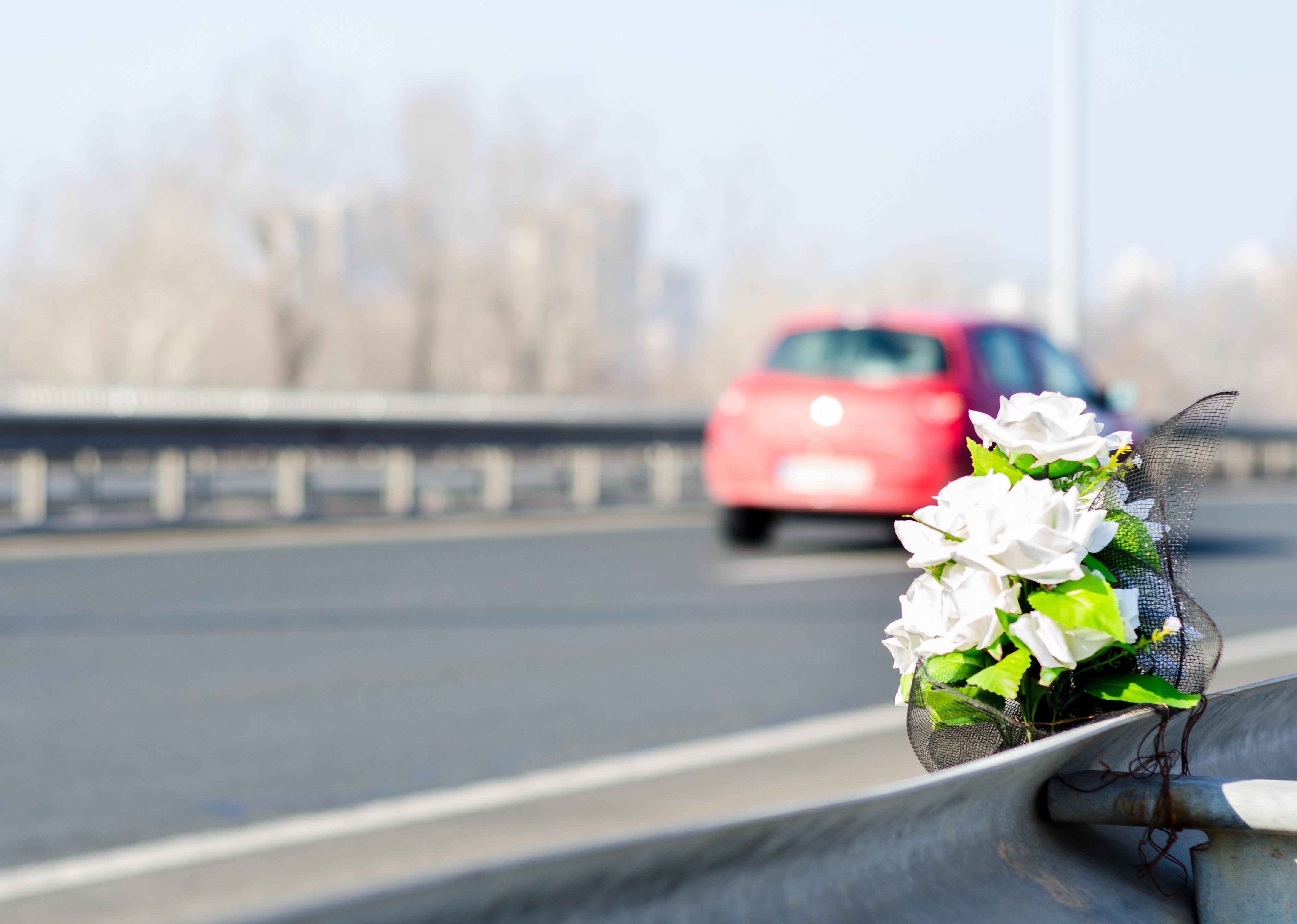 Artificial white roses flowers on the site of a car crash.