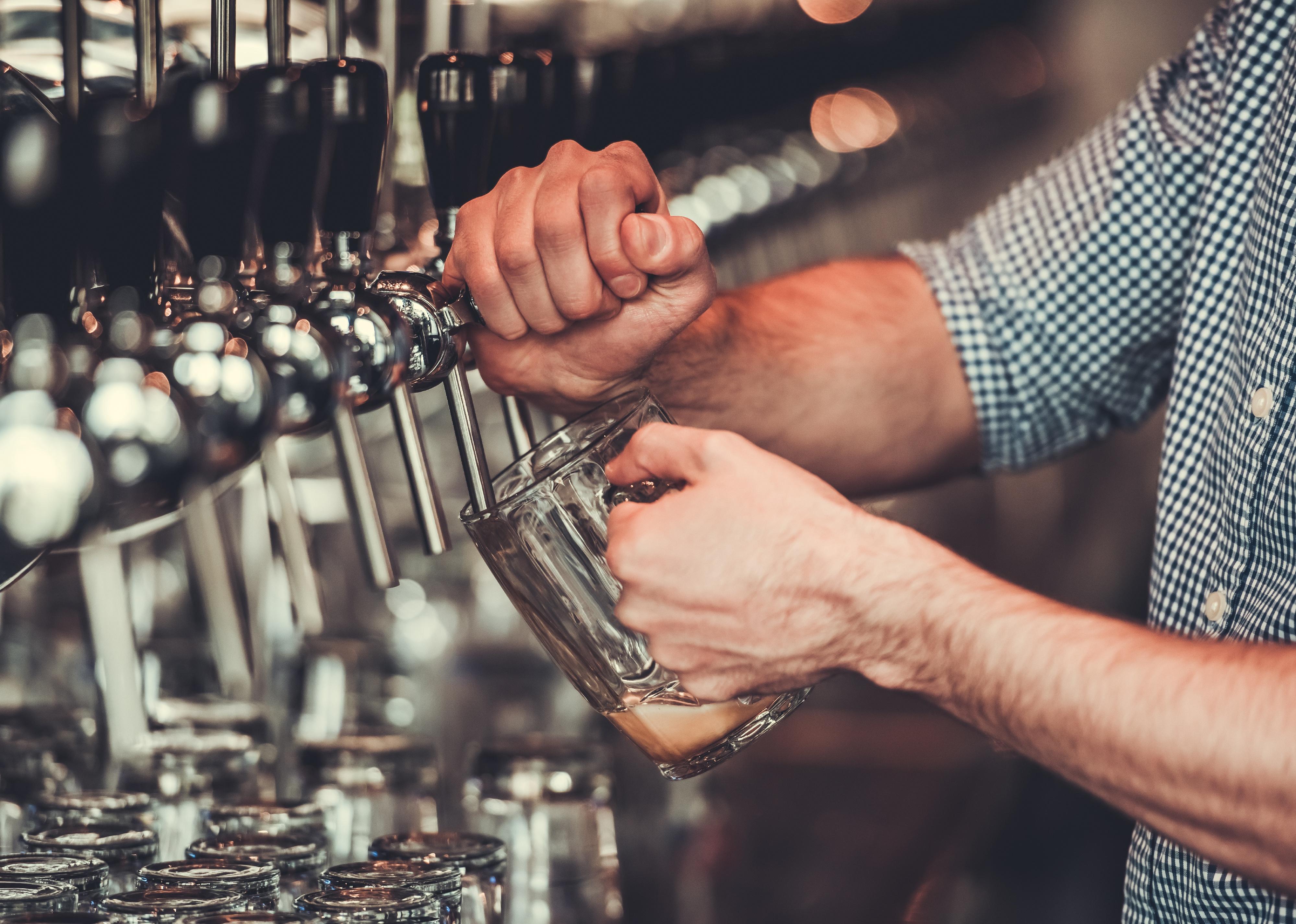 Cropped image of bartender pouring beer to the mug