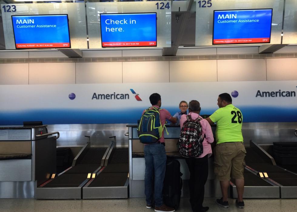 Three men check in at the American Airlines customer service counter