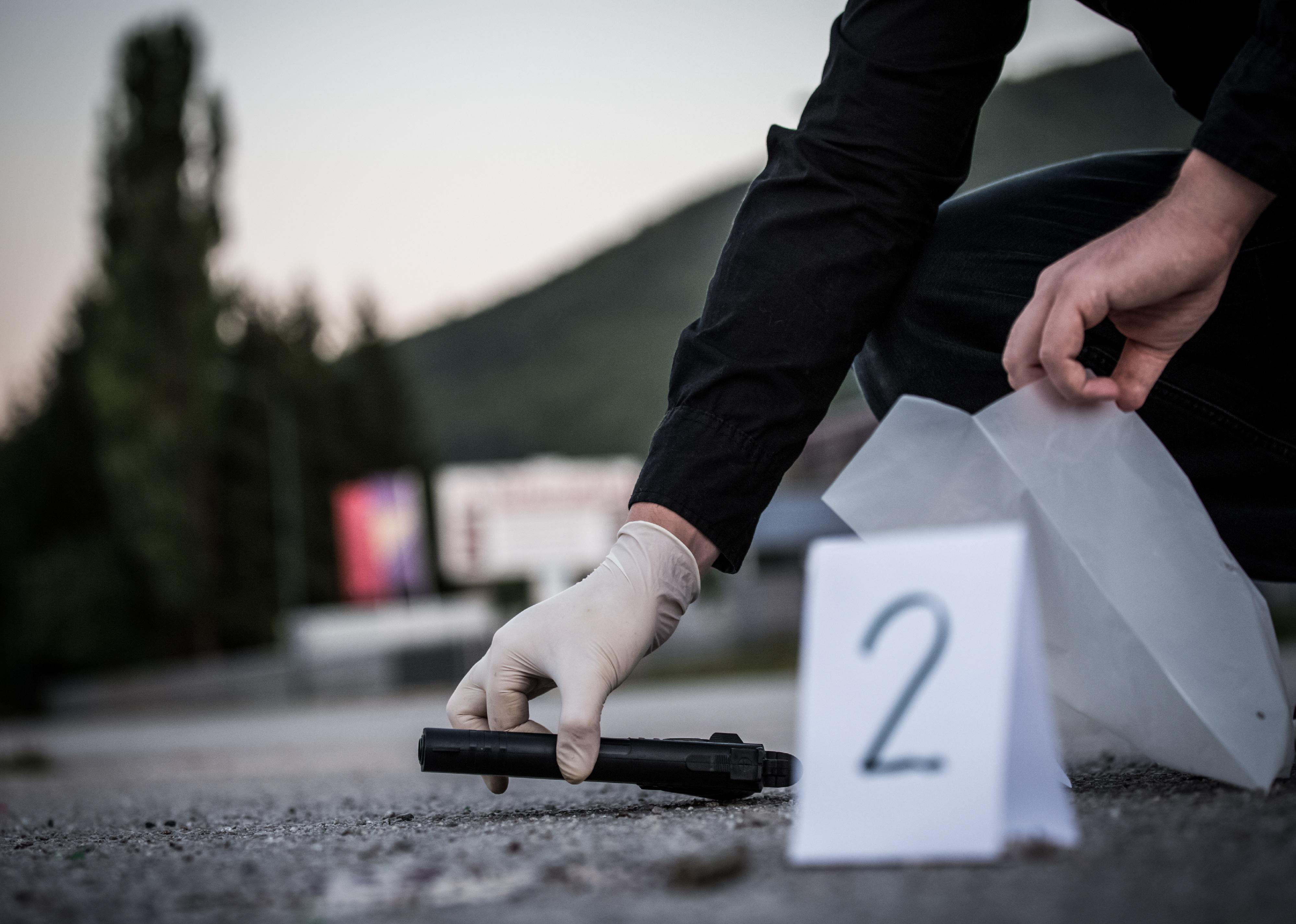 Close up of a gloved hand bagging a gun into evidence.