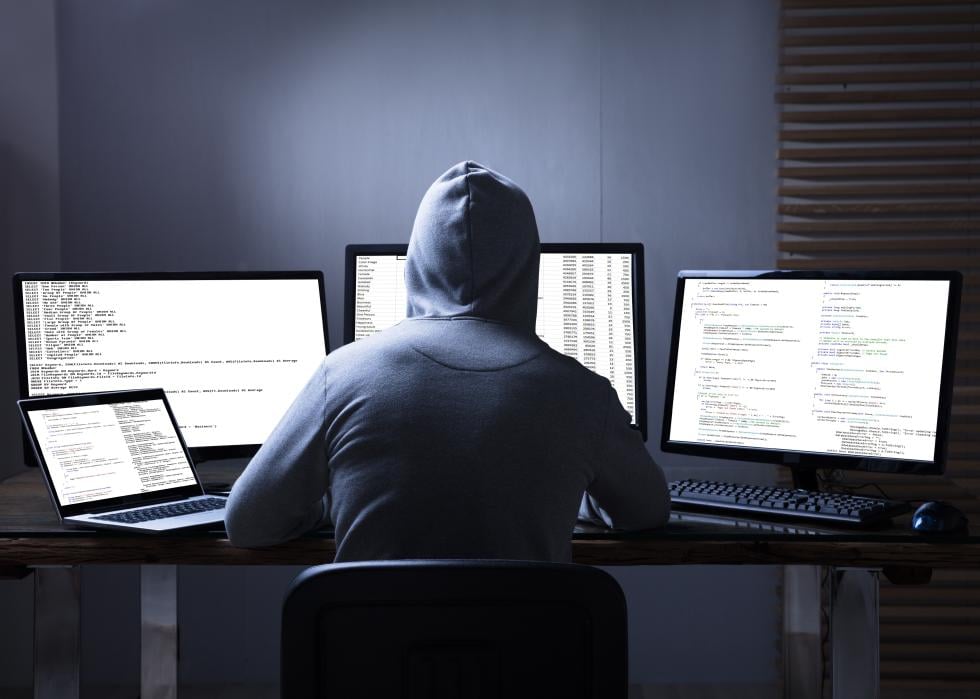 Rear view of a hacker using multiple computers