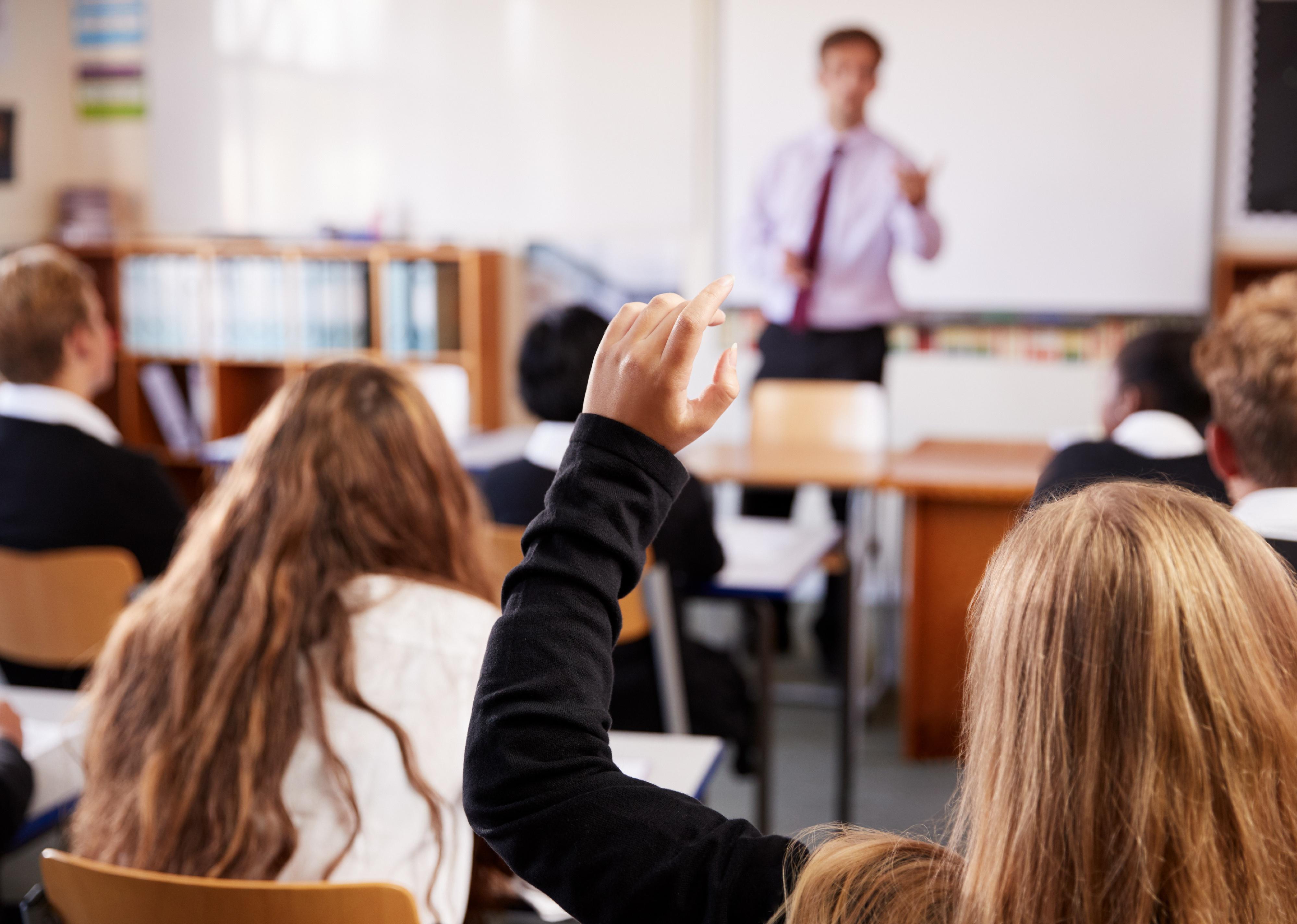 Female student raising hand in private school classroom.