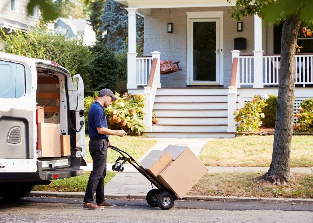 A driver delivers packages on a handtruck.