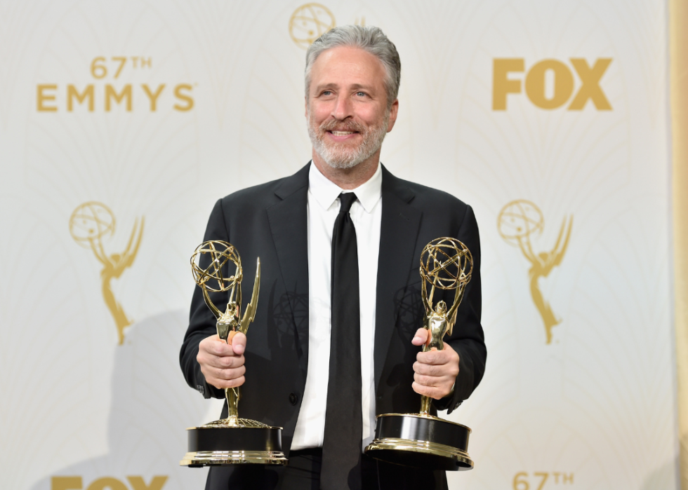 Jon Stewart poses with two Emmy awards.