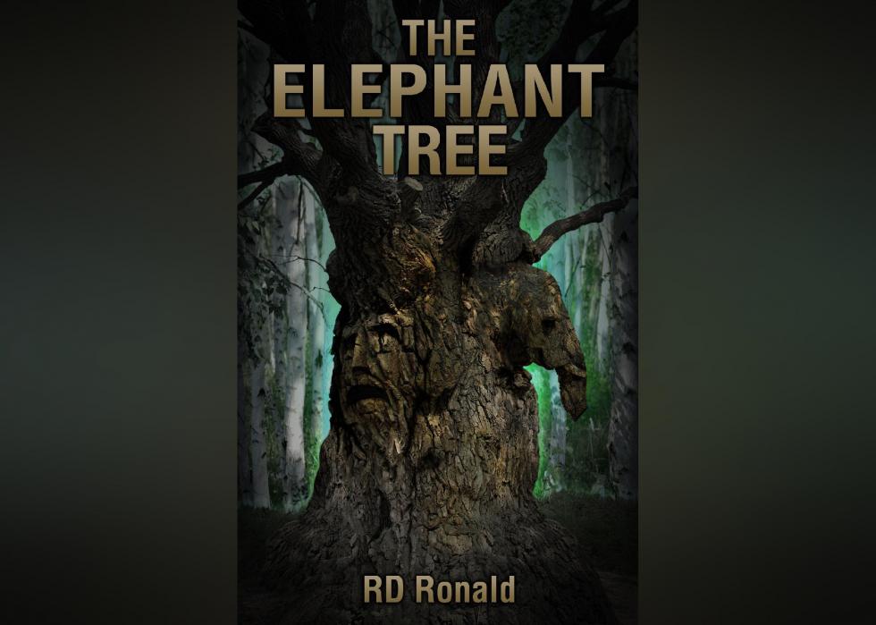 The cover shows the large trunk of a tree with an elephant and a face carved into it, in a green-glowing forest. 