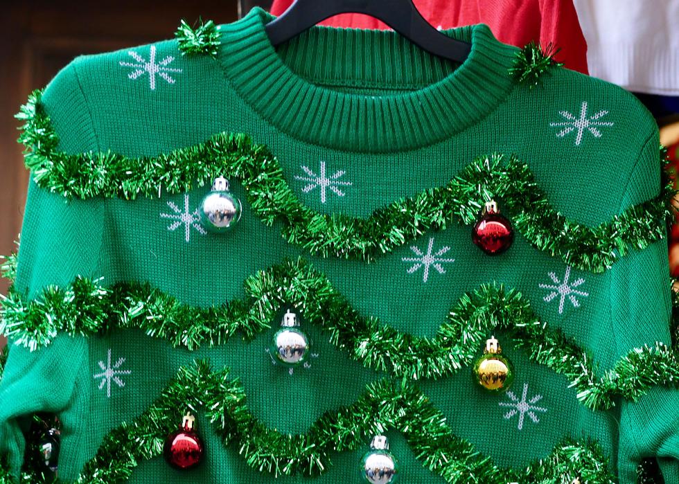 Detail of a sweater decorated with tinsel and ornaments.