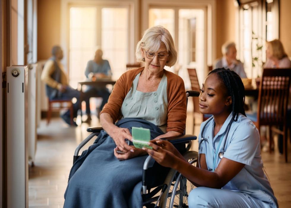 A nurse helping a woman in a wheelchair with her medication.