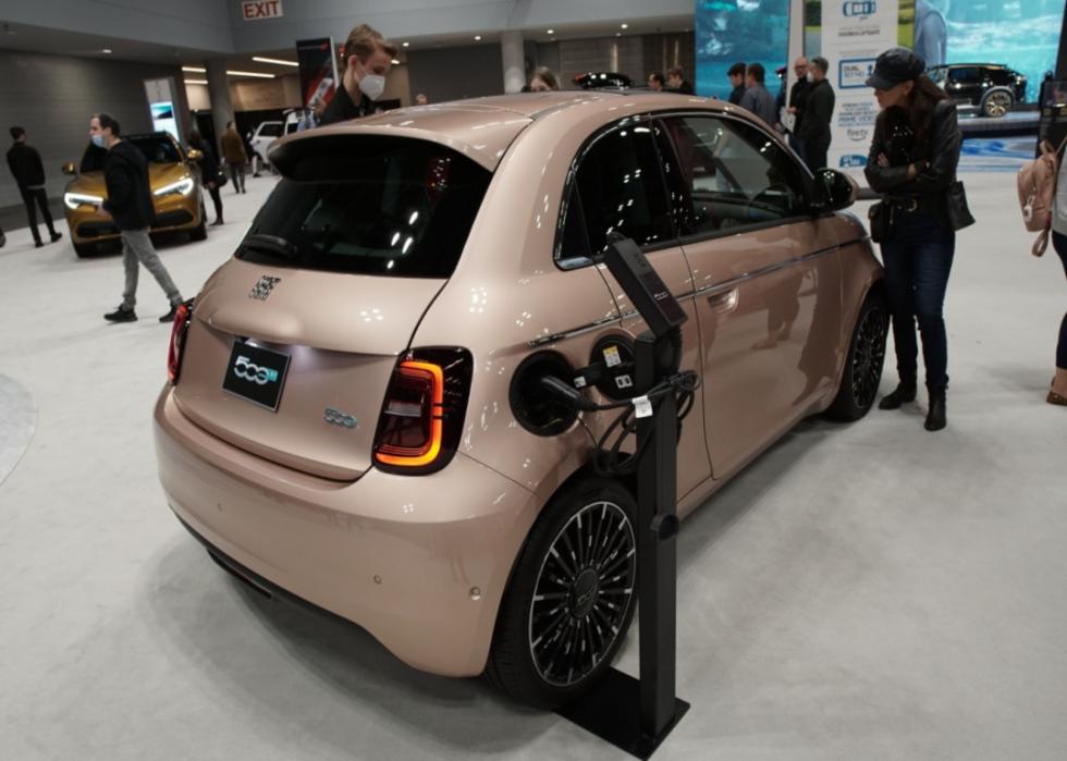 A tan electric Fiat at a car show.