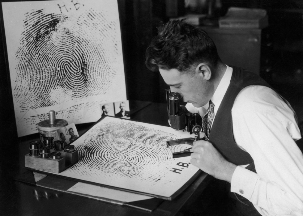 A man examining an enlarged fingerprint circa 1925.