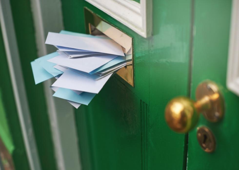 A green door with a full mail slot.