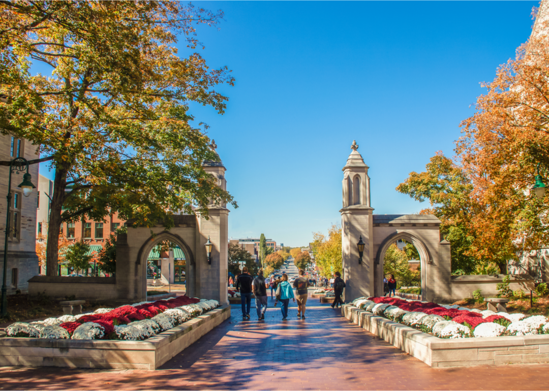 People walking thought University of Indiana gates in autumn