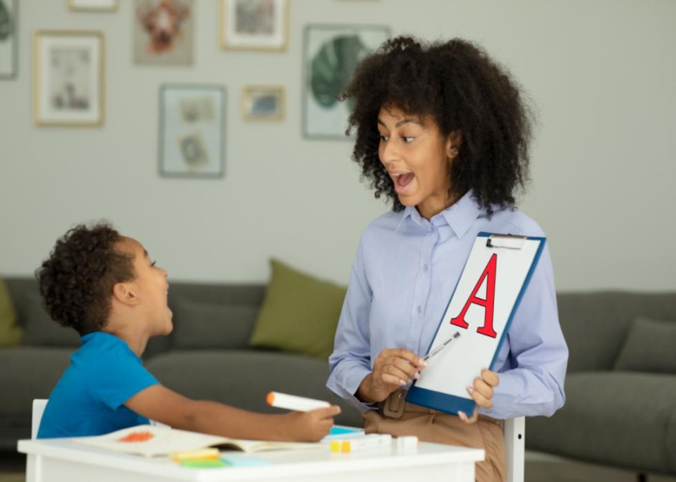 A teacher helping a child learn letters.