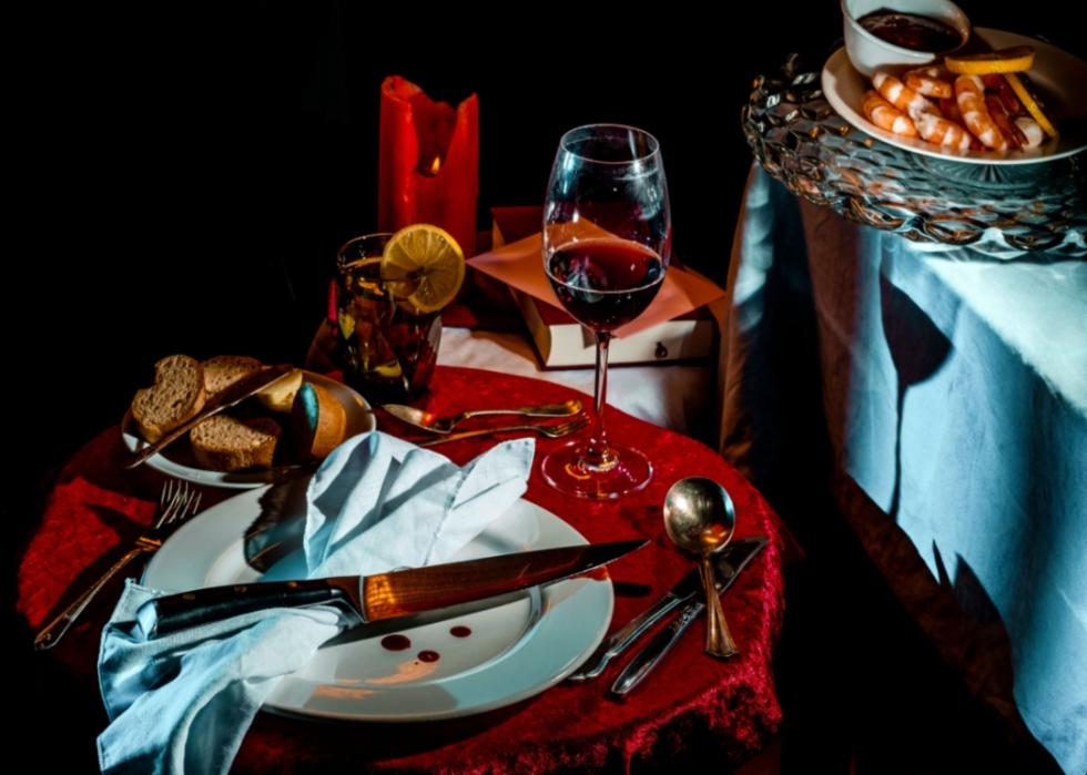 A dramatic dinner party place setting with a large knife and red drops on the plate.