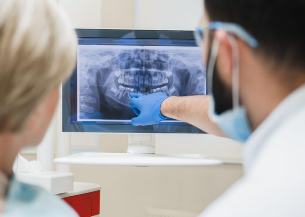 An oral surgeon showing an x-ray to a patient.