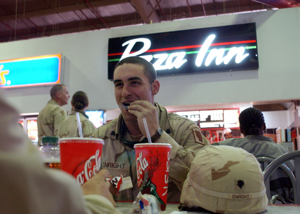 Military personnel eating at a food court with Pizza Inn in the background.