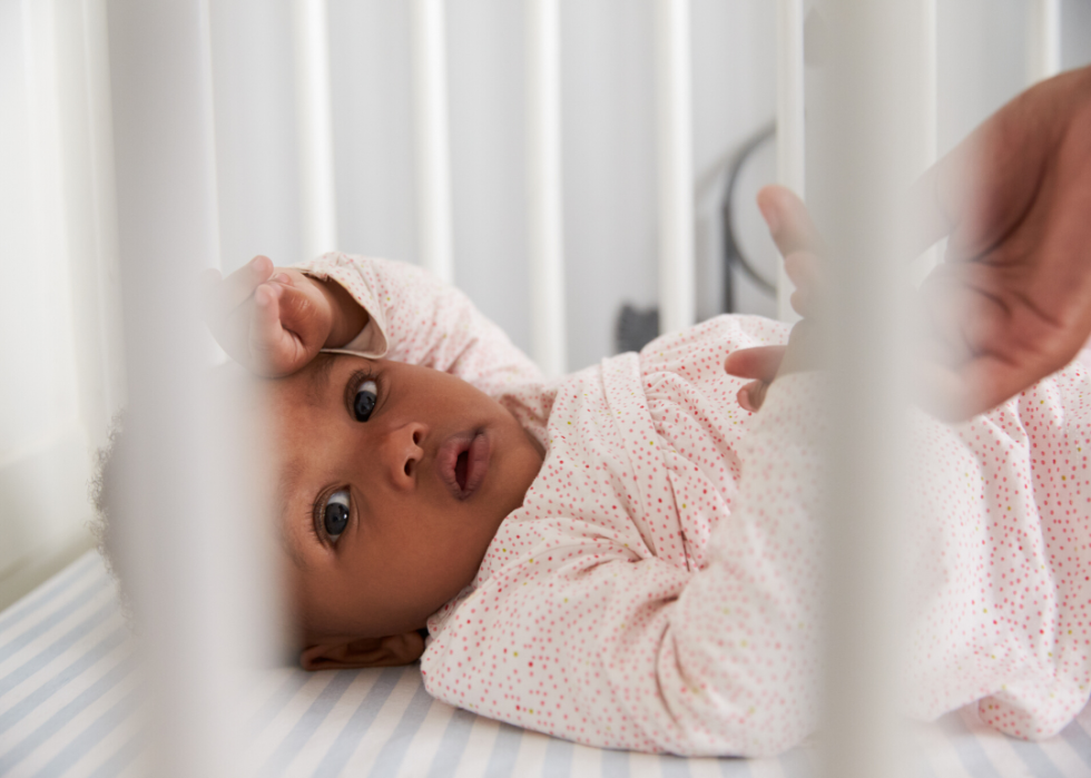 Baby girl in pink lying in crib.