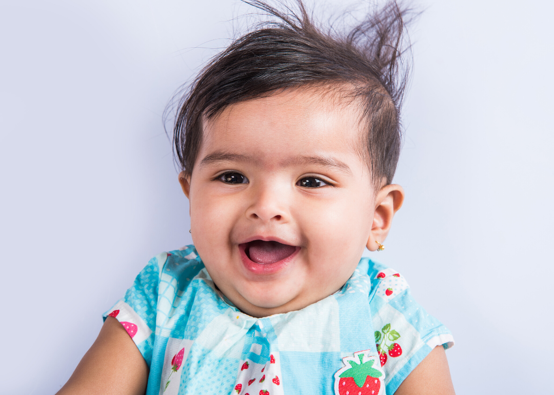 Smiling baby with blue and strawberry shirt on.