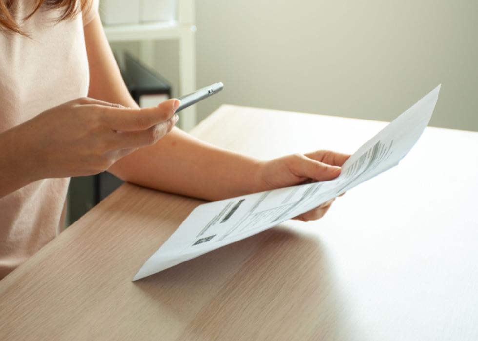 A person sat at a table scans a document with her smartphone.