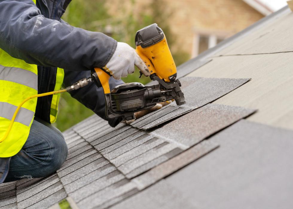 A worker installing roof tiles while dressed in protective gear