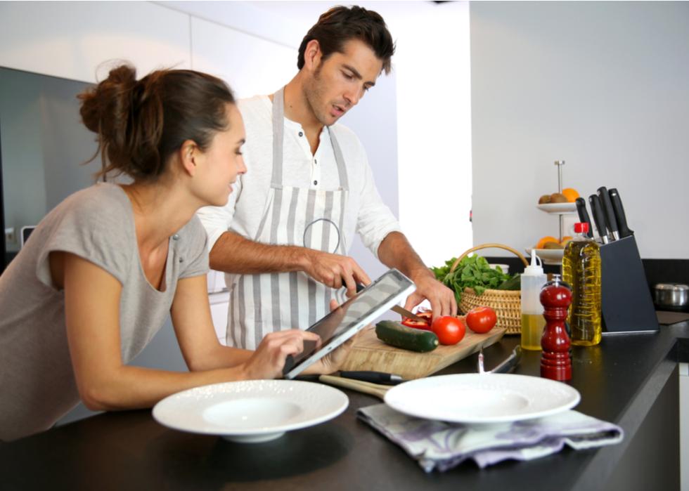 A couple in their home kitchen looking at a recipe on the internet