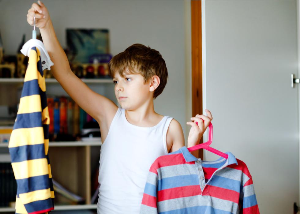 A young boy deciding which shirt to wear
