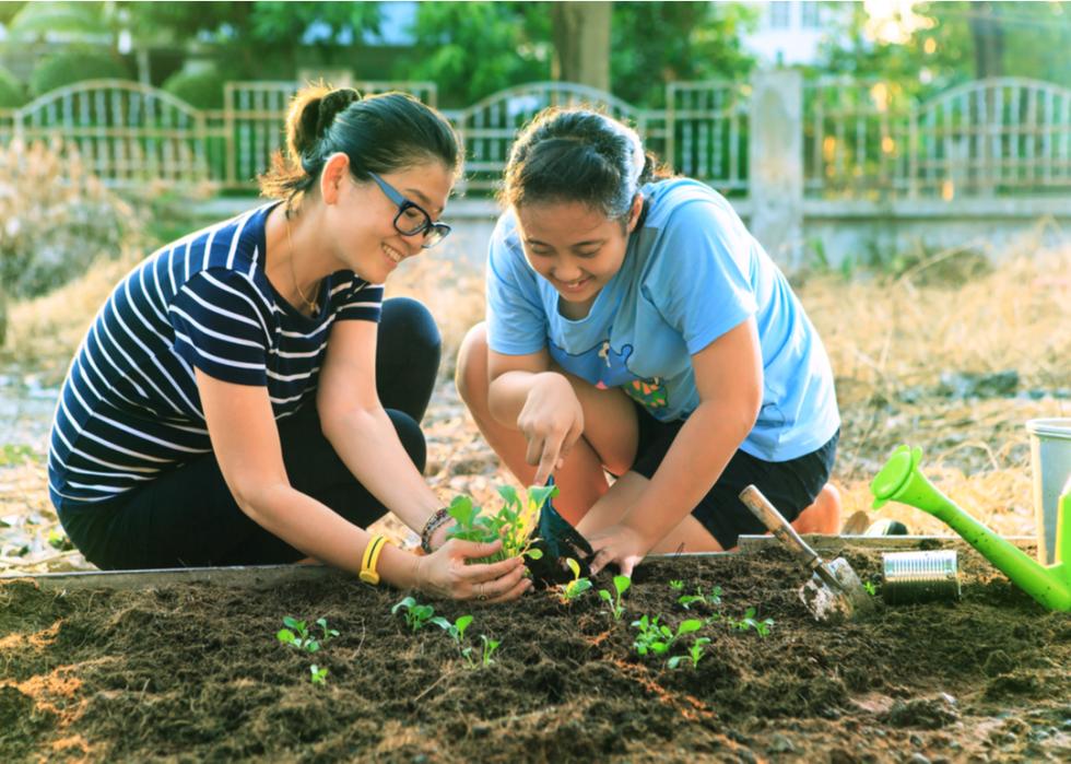 A mother and daughter planting vegetables in their home garden