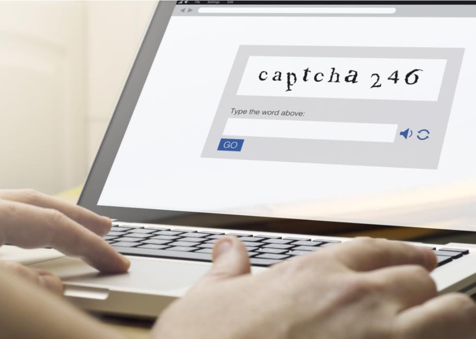 A person using a laptop with a captcha on the screen