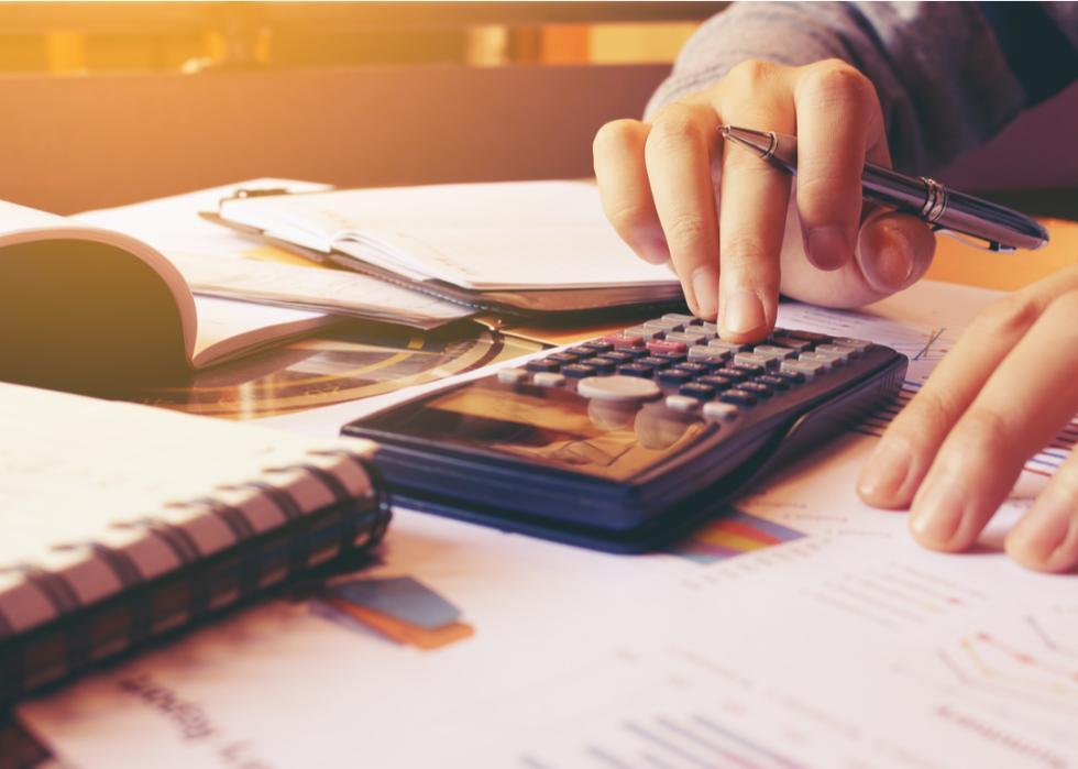 Una mujer que usa una calculadora mientras administra sus finanzas en la oficina de su casa
