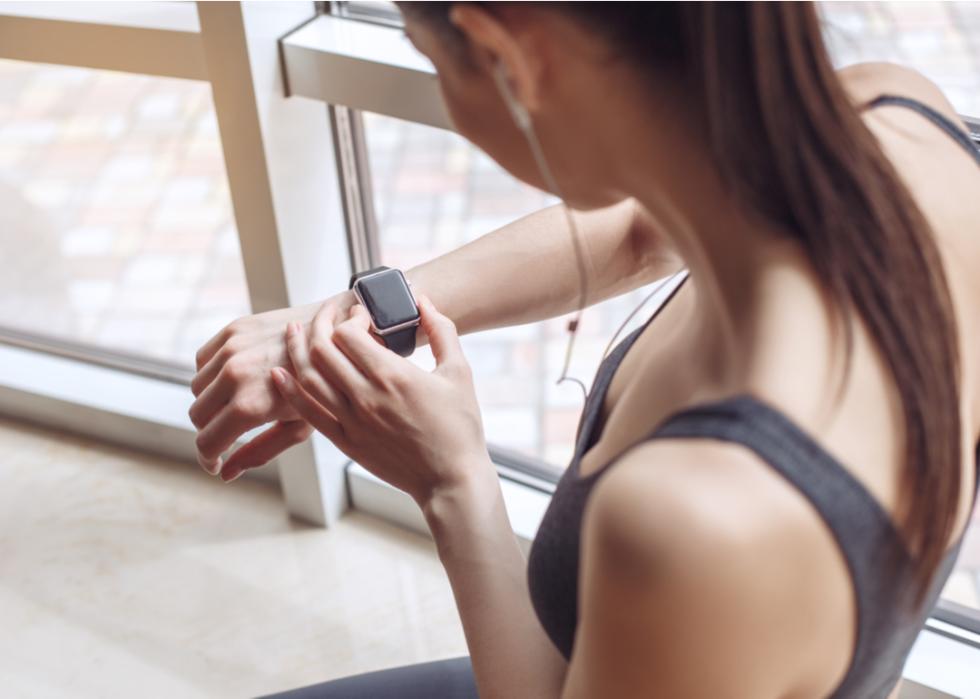 A young woman pausing from a workout to check her smart watch