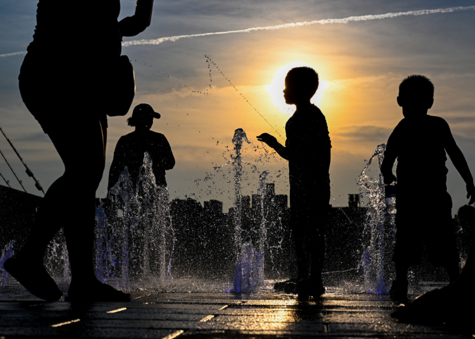 Silhouettes of children playing in water.