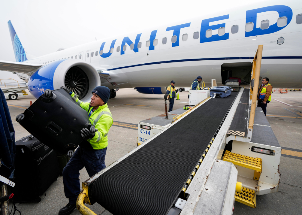 A baggage handler loading luggage onto a United plane.