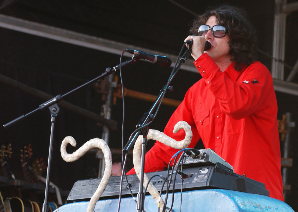 A musician wearing sunglasses sings into a mic. 