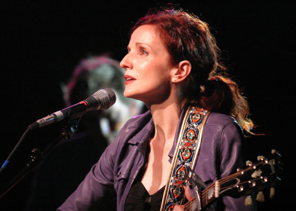 Patty Griffin sings into a mic while playing guitar. 