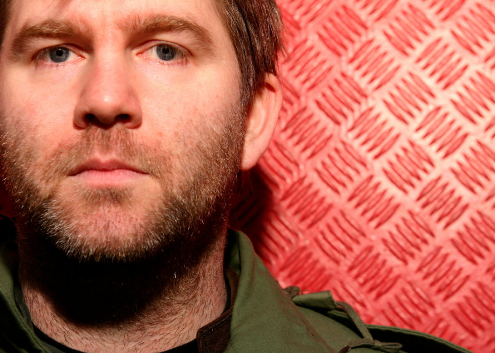 A close up of James Murphy of LCD Soundsystem in front of a red background. 