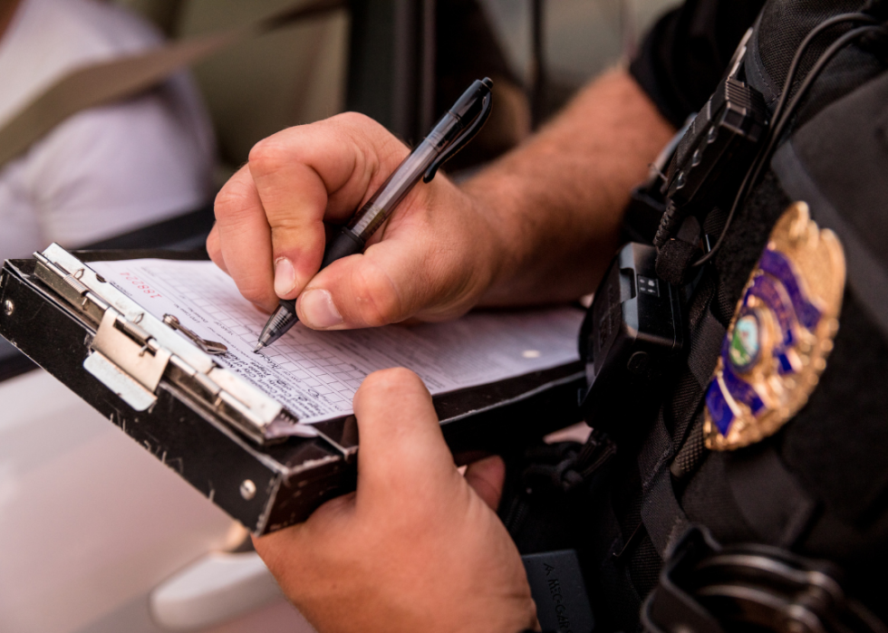 A close up of a police officer writing a ticket. 