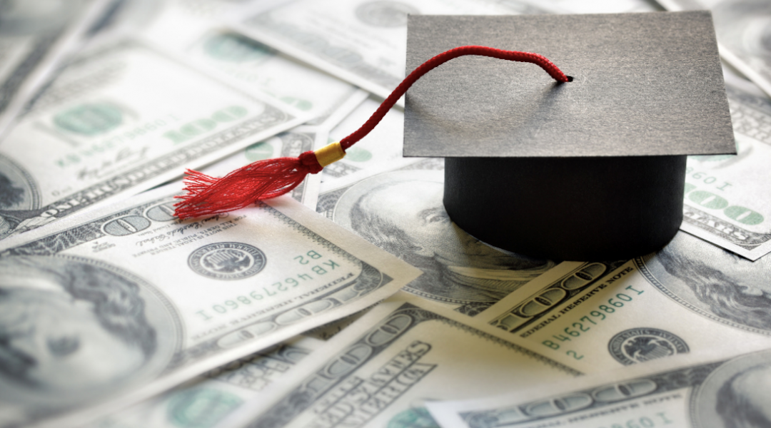 a graduation cap resting on money 